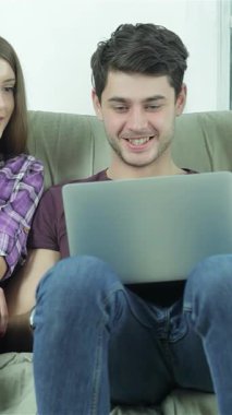 Neşeli genç yetişkinlerden oluşan bir üçlü sıcak, yumuşak doğal ışıkla yıkanmış rahat bir kanepede otururken kahkahaları ve hikayeleri paylaşıyorlar. Neşeli gülümsemeleri ve rahat tavırları, bir araya geldiklerinde dostluk ve eğlence ortamı yaratıyor.