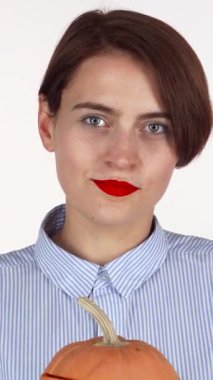 Neşeli, kırmızı dudaklı bir kadın şakacı bir şekilde yüzünü oyulmuş bir balkabağı fenerinin arkasına gizliyor, neşeli bir neşe saçıyor. Bu büyüleyici sahne, neşeli bir sonbahar ortamında gelenek ve eğlenceyi harmanlayan Cadılar Bayramı ruhunu yansıtıyor.