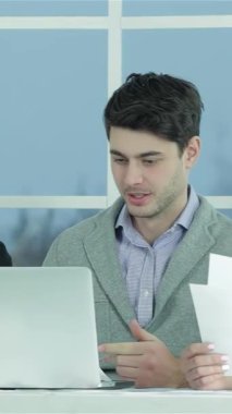 Genç profesyonellerden oluşan dinamik bir üçlü, bir erkek ve iki kadın, belgeler ve bir dizüstü bilgisayar üzerinde tutkuyla işbirliği yapıyorlar, yüzleri kararlılık saçıyor. Parlak, modern bir ofiste, atmosfer yaratıcılık ve verimlilikle uğulduyor, ilham verici.