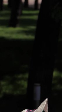 İki muhteşem beyaz kadın, biri esmer ve diğeri ateşli kızıl saçlı, parlak bir havuzun yanında canlı pembe güverte sandalyelerinde güneşleniyorlar. Şık bikiniler ve eğlenceli plaj şapkalarıyla süslenip rahatlama havası yayıyorlar.