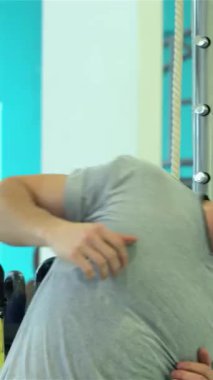 Güçlü fiziği olan kararlı genç bir adam modern ekipmanlarla çevrili canlı bir spor salonunda canlandırıcı bir omuz kemeri takmaya başlıyor. Atletik kıyafetleri ve yoğun odaklanma enerjiyi somutlaştıran, zindeliğe olan bağlılığını gösteriyor.