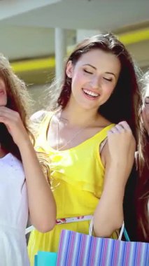 Üç modaya uygun kadın, her biri gösterişli renkli alışveriş torbaları, şık bir alışveriş merkezinin dışında hoş bir selfie paylaşıyorlar. Işıl ışıl gülümsemeleri ve bulaşıcı kahkahaları, güneşli bir günde arkadaşlığın ruhunu ve perakende terapisinin heyecanını somutlaştırıyor.