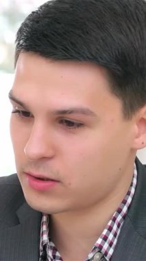 Yakın çekim genç bir çifti yakalar, keskin takım elbiseli bir adam ve profesyonel giyinmiş bir kadın, bir iş görüşmesine dalmış olarak. Yoğun ifadeleri ve yumuşak, doğal ışıklandırmaları dinamik bir atmosfer yaratarak,