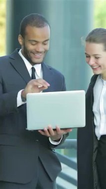 Bir çift gülümseyen iş adamı, şık giyinmiş bir adam ve bir kadın, bir dizüstü bilgisayar üzerinden canlı bir tartışmaya giriyorlar, coşku ve işbirliği yayıyorlar. Bu canlı sahne, modern bir şehir arkaplanına karşı hazırlanır.