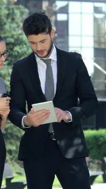 Kendine güvenen bir işadamı ve başarılı bir iş kadını, canlı bir tablet üzerinde canlı bir işbirliğine girişirler. Gülüşleri, canlı şehir zeminini aydınlatır. Şık profesyonel kıyafetler giyip, yenilik ve takım çalışmasının ruhunu somutlaştırıyorlar.