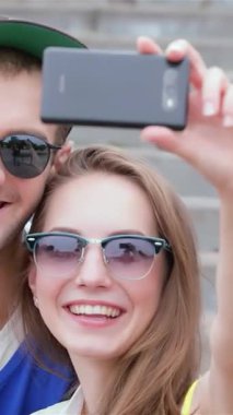 Neşeden parlayan üç canlı arkadaş, canlı bir selfie çekmek için güneşin öptüğü adımlarda toplanıyor, onların ışıl ışıl gülüşleri sahneyi aydınlatıyor. Bu keyifli an, dostluk ve kaygısız yaz günlerini özetliyor.