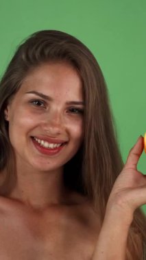 Canlı yarı turuncu renkte, sağlığını ve canlılığını simgeleyen uzun, dalgalı saçları olan ışıl ışıl genç bir kadın. Canlı yeşil bir zemin üzerine kurulmuş bu görüntü, refahın, taze meyvelerin ve kaygısız bir yazın özünü yakalar.