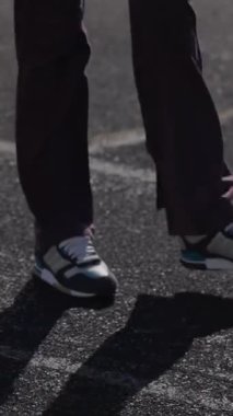 Canlı atletizm kıyafetleri giymiş iki ateşli genç kız, enerjik bir şekilde güneş ışığı alan bir pistte ısınma egzersizleri yapıyorlar, güç ve coşku yayıyorlar. Renkli spor ayakkabıları dokulu yüzeyde sekiyor, gençliği somutlaştırıyor.