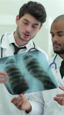 Zarif, iyi ışıklandırılmış bir hastane ortamında üç kendine güvenen doktor ve bir kadın sağlıklı akciğerlerin röntgenini inceliyor. Odaklanmış ifadeleri ve beyaz önlükleri hasta bakımında mükemmelliğe olan bağlılıklarını yansıtıyor.