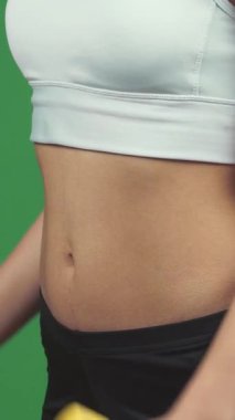 Bu enerjik yakın çekim, canlı yeşil bir krom arka planda canlı sarı halterler kaldıran, kaslı kararlı bir kadını gösteriyor. Yoğun odaklanma ve güçlü kavrama gücü ve motivasyonu, özü somutlaştırıyor.