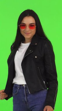 Uzun siyah saçlı, modaya uygun güneş gözlüklü şık bir kadın kameraya doğru şık bir alışveriş çantası tutarken parlak yeşil renkli bir arka plana yaslanıyor. Bu enerjik portre perakende terapisinin heyecanını özetliyor.