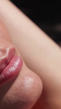 Büyüleyici bir yakın çekim, neşeli bir genç kadın, mutlu bir gülümseme, sıcak güneş ışığı altında parlayan güneşten öpülmüş teni. Işıldayan havuzu yansıtan şık güneş gözlükleriyle yaz tatilinin kaygısız ruhunu ve coşkusunu somutlaştırıyor.