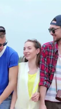 Üç neşeli arkadaş, canlı yaz kıyafetleri içinde, birlikte parlak mavi bir gökyüzünün altında yürüyorlar, kahkahaları arkadaşlığın neşesini yansıtıyor. Neşeli ifadeler ve şık kıyafetler, canlı bir atmosfer yaratıyor, özünü yakalıyor.