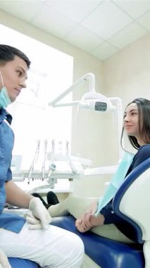 Parlak ve modern bir dişçi kliniğinde, genç, kendine güvenen bir dişçi ve gülümseyen bir hasta, olumlu ve güven saçan bir başparmaklarını paylaşıyor. Bu canlı etkileşim, sağlığın mutlulukla buluştuğu dostça diş bakımının sıcaklığını vurgular.