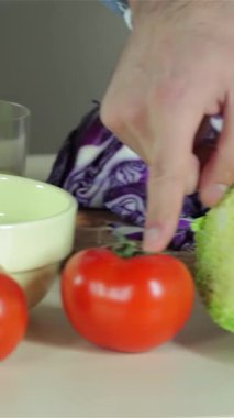 Canlı bir mutfakta, genç, gülümseyen arkadaşları, lezzetli bir akşam yemeği için parlak kırmızı domates ve çıtır biber gibi taze, renkli sebzeleri neşeyle doğrarken yakalar. Hava kahkaha ve sıcaklıkla dolu. Güzelliğini gösteriyor.