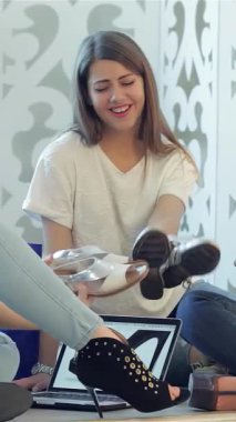 Üç modaya uygun kız arkadaş, canlı alışveriş torbaları ve bir dizüstü bilgisayarla çevrili, rahat bir katta otururken neşeyle şık ayakkabılar deniyorlar. Kahkahalar havayı dolduruyor. Zevkli anları paylaşıyorlar. Benzersiz tarzlarını sergiliyorlar.