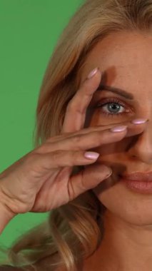 Bu çarpıcı yarım-yüz portresi, güzel olgun bir kadının özünü yakalar, mükemmel manikürlü bir elle yanağını okşar canlı yeşil renkli bir arka plana karşı. Görüntü, özgüven ve entelektüellik yayar.