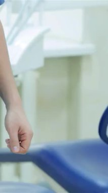 Neşeli bir hasta zarif, modern bir diş muayenehanesinde dişçiyle coşkuyla tokalaşıyor güven ve profesyonellik saçıyor. Bu davetkar sahne, gelişmiş diş aletlerini ve lüks mavi bir diş sandalyesini ön plana çıkarıyor ve rahatlatıcı bir atmosfer yaratıyor.