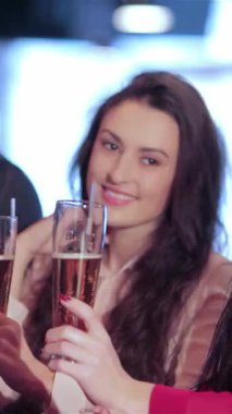 Canlı bir arkadaş üçlüsü, iki kadın ve bir erkek, bardaklarını hareketli bir barda tokuştururken bulaşıcı bir kahkaha paylaşıyorlar, neşeli anları kutluyorlar. Elektrik atmosferi en sevdikleri futbol takımı için tezahüratlarla dolu.