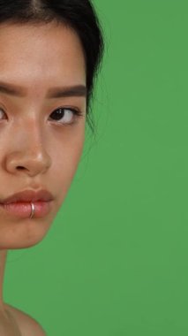 Parlak, uzun siyah saçlı, nefes kesici Asyalı bir kadın canlı yeşil bir renk perdesine karşı tutkuyla çığlık atıyor. Ham duygular fırtınasını somutlaştırıyor. Öfke ve derin üzüntünün büyüleyici bir karışımını yayıyor.