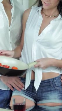 Sıcak bir mutfakta neşeli bir kadın, erkek arkadaşına taze, canlı domateslerle dolu parlak bir tava sunar. Kahkahaları ve ortak heyecanları, yemek pişirmenin zevkini vurgulayan samimi bir atmosfer yaratıyor.