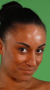 Büyüleyici bir Afrikalı kadın neşeyle ışıldıyor, neşeli gülüşü çerçeveyi canlı yeşil renkli bir arka plana doğru aydınlatıyor. Işıl ışıl cildi ve anlamlı gözleri bir güven ve canlılık hissi veriyor, izleyicileri kendisiyle paylaşmaya davet ediyor.