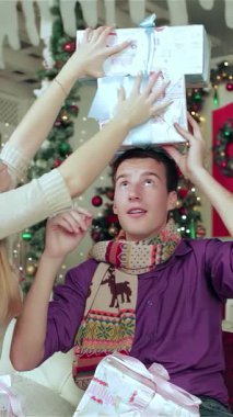 Peri ışıkları ve canlı süslemelerle donatılmış rahat bir Noel odasında, neşeli bir çift birbirlerine güzel paketlenmiş hediyeler veriyor, yüzleri heyecanla parlıyor. Çarpıcı bir Noel ağacı tarafından vurgulanan ılık ortam,