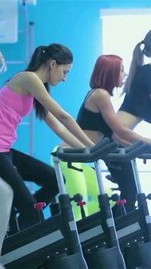 Parlak mavi duvarlarla süslenmiş canlı bir spor salonunda, genç bir kız susuzluğunu ferahlatıcı suyla giderirken, atletik arkadaşları hareketsiz bisikletlerle heyecan verici bir bisiklet seansı düzenliyor. Bu dinamik sahne enerji ve yoldaşlık yayar.