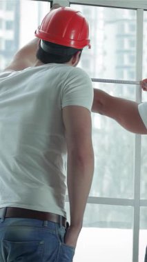 Parlak, havadar bir dairede, kendini adamış iki işçi pencereleri dikkatlice ölçüyorlar ve gerekli onarımlara hazırlanıyorlar. Odaklanmış ifadeleri ve kusursuz takım çalışmaları yakınlarda sağlam bir merdiven ile bu alanı değiştirmeye olan bağlılıklarını vurguluyor.