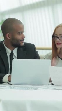 Sivri iş kıyafetleri içinde dört genç profesyonelden oluşan canlı bir grup, parlak ve modern bir ofiste aromatik kahve fincanları üzerine yenilikçi fikirleri hevesle paylaşıyor. Animasyon jestleri ve sıcak gülümsemeleri bir davet yaratıyor.