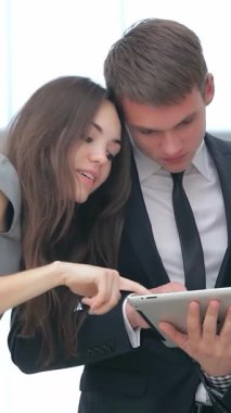 Bir kadın ve iki erkeğin yer aldığı canlı bir grup, etkileyici iş sonuçlarını parlak bir tablet üzerinde hevesle analiz ediyor. Neşeli ifadeleri ve işbirlikçi enerjileri heyecan ve başarıyı parlak bir şekilde yayar.