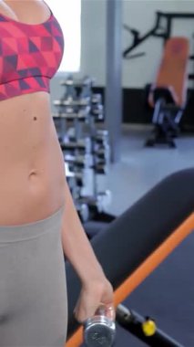 Odaklanmış, kızıl saçlı beyaz bir kadın spor salonunda kaslarını tutkuyla yontuyor. Güç ve kararlılık saçıyor. Göz alıcı spor kıyafetleriyle donanmış bir halteri sarsılmaz bir hassasiyetle kaldırıyor ve özünü somutlaştırıyor.