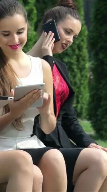 Üç kendine güvenen iş kadını güneşli bir park bankında oturmuş parlak aletlerini kullanarak fikirleri tartışıyorlar. Şık kıyafetleri ve ışıl ışıl gülümsemeleri yemyeşil bir vahada canlı ve işbirlikçi bir ruhu temsil ediyor.