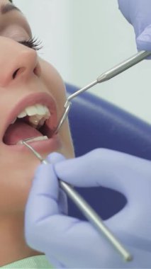 Neşeli genç bir kız, parlak, davetkar bir klinikte ışıldayan profesyonel aletlerle çevrelenmiş diş kontrolünden geçerken ışıl ışıl bir gülümsemeyle ışıldıyor. Bu canlı sahne, oral sağlığın korunması ve özgüvenin gösterilmesi sevincini vurguluyor.