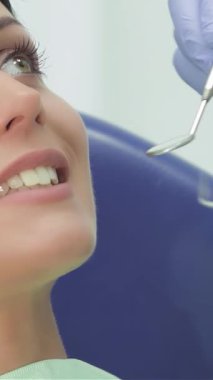 Parlak ve davetkar bir dişçi kliniğinde, mavi eldivenlerle süslenmiş yetenekli bir dişçi, özgüven ve sakinlik saçan genç bir kızın dişlerini titizlikle inceliyor. Bu samimi an, göz kamaştırıcı bir şekilde diş bakımının hassasiyetini gösteriyor.