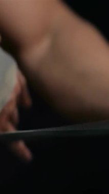 Yakın plan çekimde kaslı bir adamın ellerini idman kemerini ustalıkla sarar, güçlü pazılarını ve keskin fiziğini vurgular. Çarpıcı siyah arkaplan, egzersiz hazırlıklarının yoğunluğunu arttırıyor ve ilham verici bir atmosfer yayıyor.