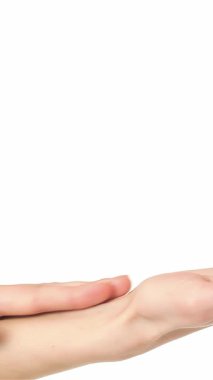 Nazik bir şekilde avuçlarını okşayan, narin parmaklarının zarafetini vurgulayan genç, beyaz bir kadının büyüleyici yakın çekimi. El değmemiş beyaz arka plan, sakin atmosferi güçlendiriyor. Rahatlama ve kendine bakmanın hislerini uyandırıyor.