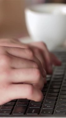 Kafkasyalı genç bir adam, tesadüfen giyinmiş, yakındaki sıcak bir kafede, sıcak bir fincan kahveyle bilgisayarında yoğun bir şekilde daktilo çekiyor. Odaklanmış ifadesi ve rahat duruşu verimlilik ve konforun mükemmel bir karışımını yaratarak izleyicileri buna davet ediyor.