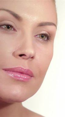 Bu zarif yakın plan beyaz bir kadını yakalıyor, narin elleri narin beyaz bir zemin üzerinde ışıl ışıl parlayan tenini okşuyor. Görüntü doğal güzellik ve zarafet yayar, büyüleyici yeşil gözlerini ve yumuşak gözlerini ortaya çıkarır.