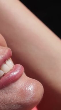 Neşeli beyaz bir kadın, sıcak yaz güneşinin altında, ışıldayan bir havuzun yanında güneşlenirken mutluluk saçıyor. Parlak yeşil güneş gözlükleri göz kamaştırıcı gülüşünü ve güneş yanığı tenini vurguluyor, tasasız yaz neşesinin ruhunu yakalıyor.