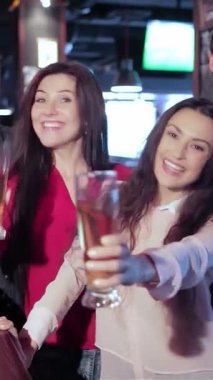 Canlı bir sahnede dört eski arkadaş, iki erkek ve iki kadın canlı bir barda coşkulu bir şekilde kadeh kaldırıyorlar. Parlak gülümsemeleri ve barın sıcacık parıltısı dostluğu ve heyecanı kutlayan davetkar bir atmosfer yaratıyor.