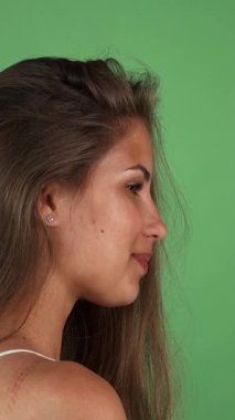 Işıl ışıl genç bir kadın, uzun, dalgalı saçlar ve güneşten yanmış bir tenle omuzlarının üzerinden canlı yeşil bir arka plana neşeyle bakıyor. Kusursuz cildi ve bulaşıcı gülüşü pozitiflik ve kendine güveni seyircileri güzelliği kutlamaya davet ediyor.