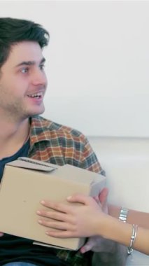 Yeni evlerinde paketlenmemiş kutularla çevrili rahat koltuklarında heyecan dolu neşeli genç bir çift. Paylaştıkları mutluluk anları, karton bir kutu tutmaları, yeni başlangıçların heyecanını ve aşklarının sıcaklığını sembolize eder.