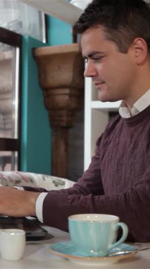 Kafkasyalı rahat bir adam, zarif bir laptopla işini bitirdikten sonra sıcak havanın tadını çıkararak büyüleyici bir kafede kollarını uzatır. Yanında nefis bir fincan espresso ile sahne verimliliğin özünü güzel bir şekilde yakalıyor.