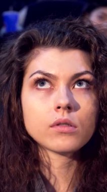 Çekici kıvırcık saçlı genç bir kadın perdeye dikkatle bakıyor loş bir sinemada tereyağlı patlamış mısırın tadını çıkarıyor. Şaşkın bakışları heyecan ve neşe saçıyor, rahat bir gecenin ortasında sinemanın heyecanını mükemmel bir şekilde yakalıyor.