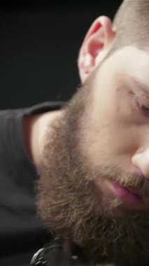 Şık sakallı ve yoğun odaklı uzman bir berber şık bir berber dükkanında şık saç kesimi ve sakal ustalıkla bir adam yaratıyor. Titreşimli atmosfer yaratıcılık ve bağlantı yayıyor, tımar sanatının ve