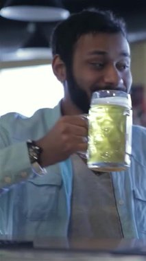 Coşkulu iki erkek futbol fanatiği, coşkulu bir barda keyifle buzlu bira bardaklarını kaldırarak heyecan ve dostluk saçıyorlar. Neşeli atmosfer kahkahalarla ve maçın heyecanıyla doludur. Dostlar içki içerken ve paylaşırken yeniden bir araya gelirler.