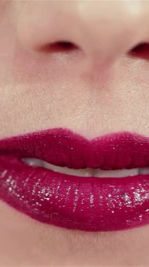 Büyüleyici bir yakın plan beyaz kadın öpücüğü üflüyor, tatlı dudakları parlak kırmızı rujuyla ışıldıyor yumuşak, pohpohlayıcı bir ışığın altında. Bu büyüleyici portre onun kusursuz cildini ve büyüleyici bakışlarını yakalıyor.