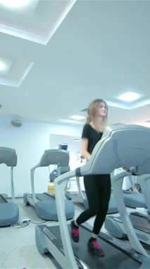 Kendini adamış dinamik bir grup sporcu, modern bir spor salonunda enerji ve kararlılık saçan canlandırıcı bir koşu bandı egzersizi yapıyor. Hareketli atmosfer, genç erkek ve kadınların şık spor kıyafetlerini sergiliyor.