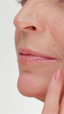 Zarif, orta yaşlı bir kadının büyüleyici yakın çekimi kusursuz cildini okşuyor, el değmemiş beyaz bir zemine kuruluyor. Işıltılı teni ve sakin ifadesi güzellik ve kendine bakım yayıyor. Cildin önemini vurguluyor.